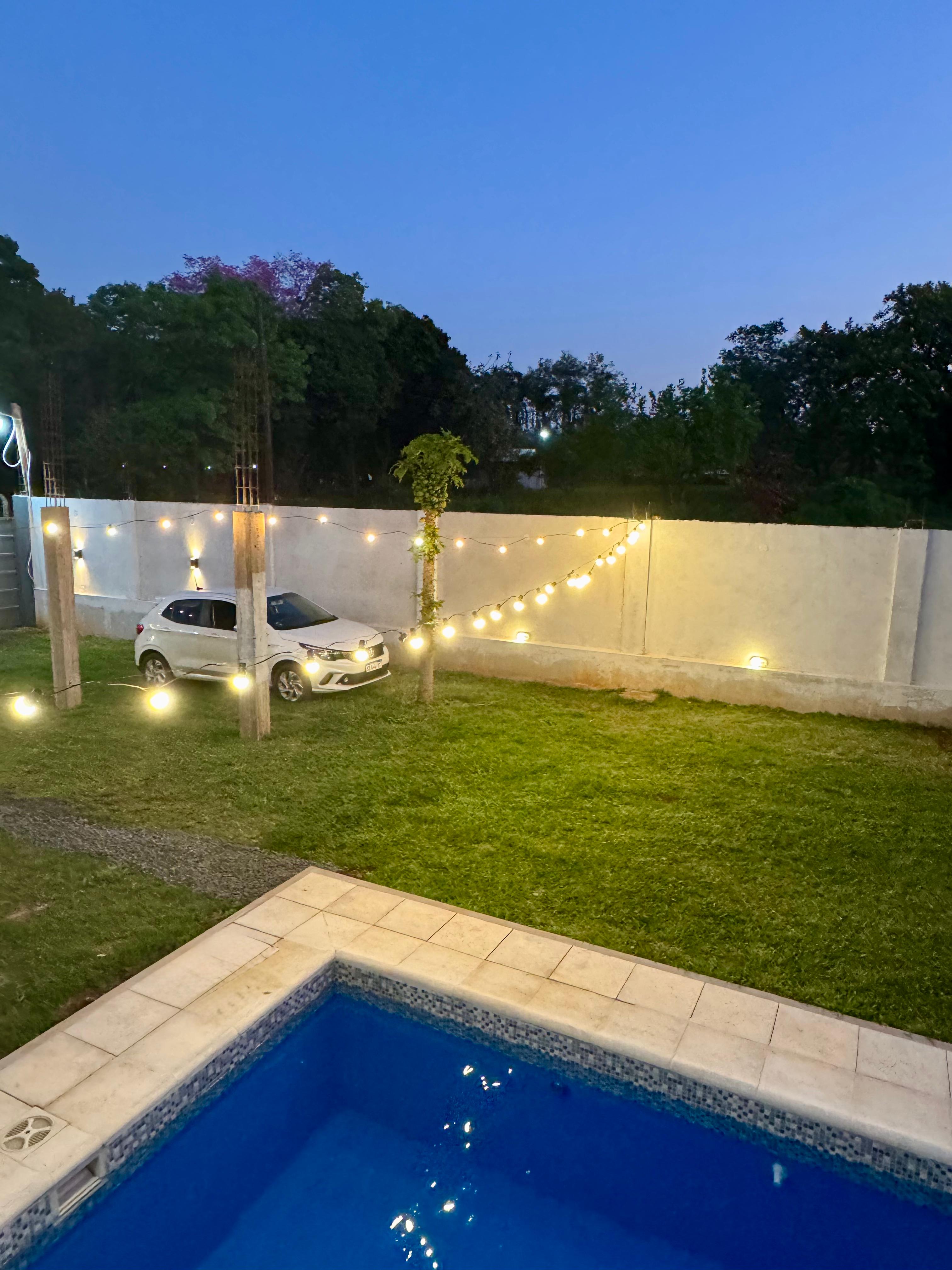 Vista nocturna del jardín y piscina